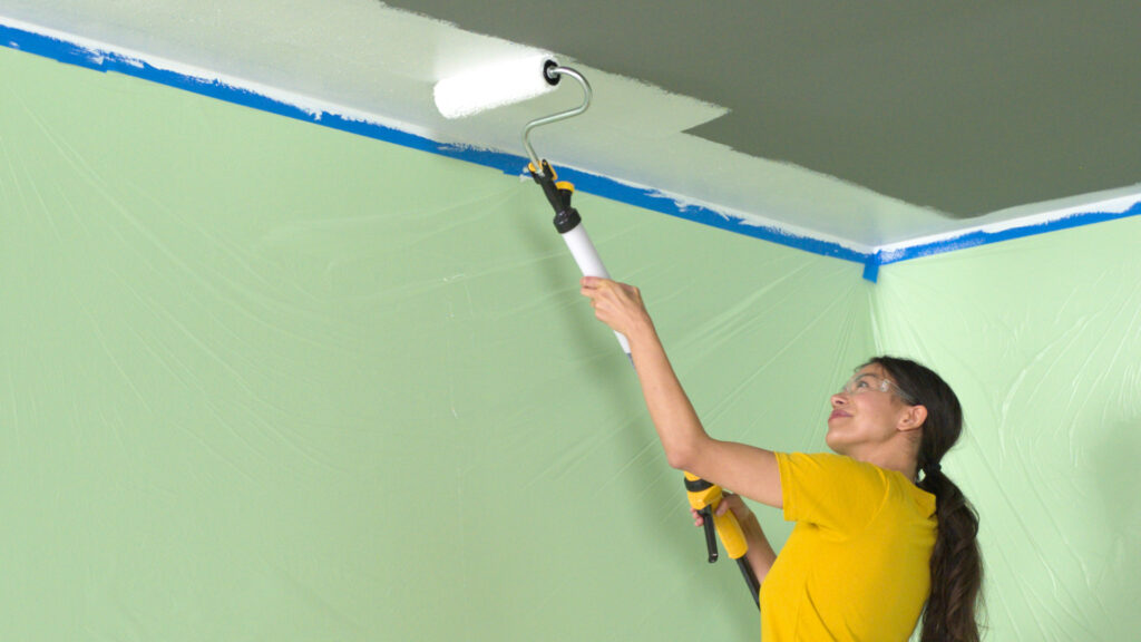 person painting a ceiling with the PaintStick EZ Roller